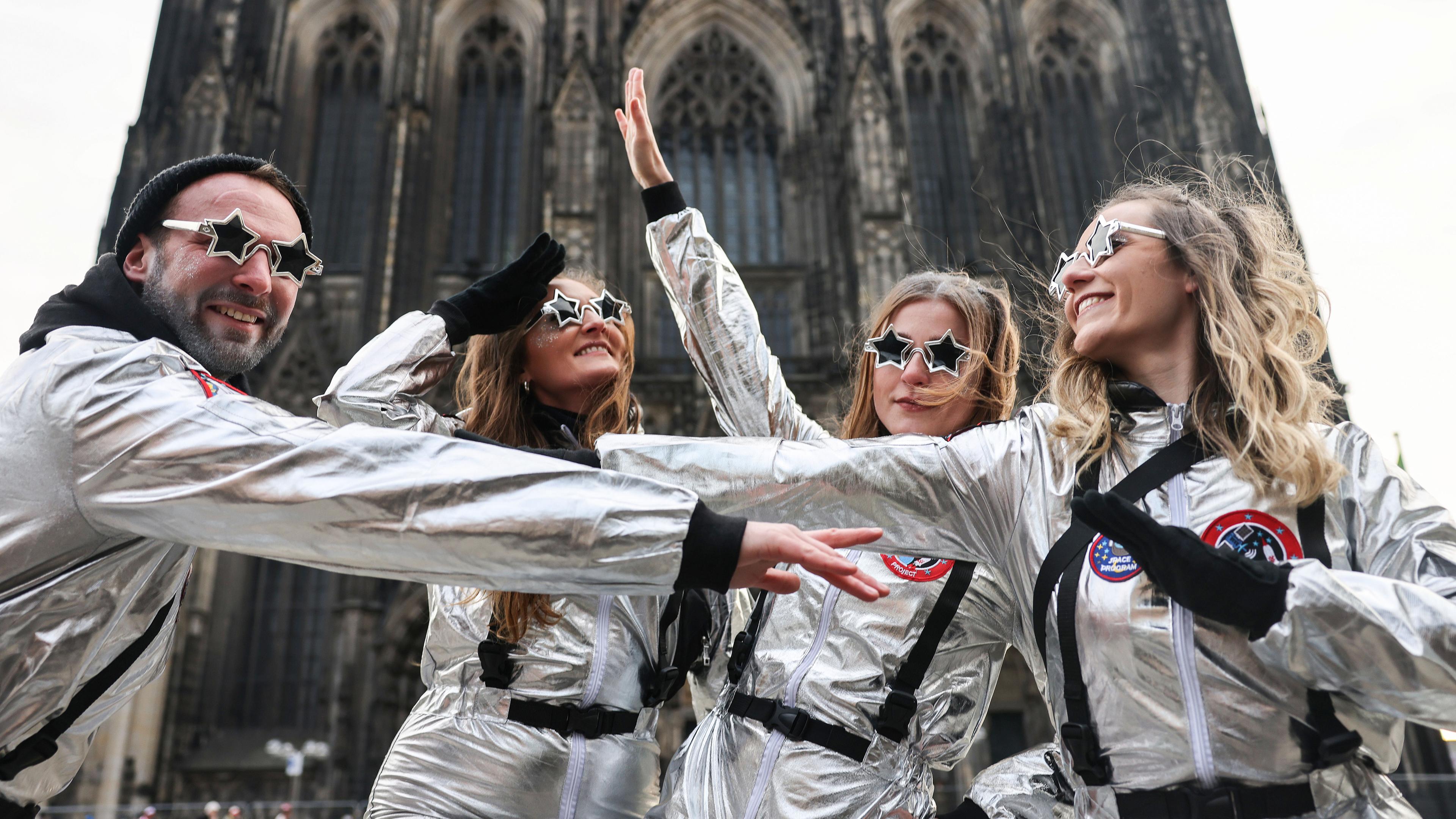 Als Astronauten verkleidete Karnevalisten stehen vor dem Dom. 