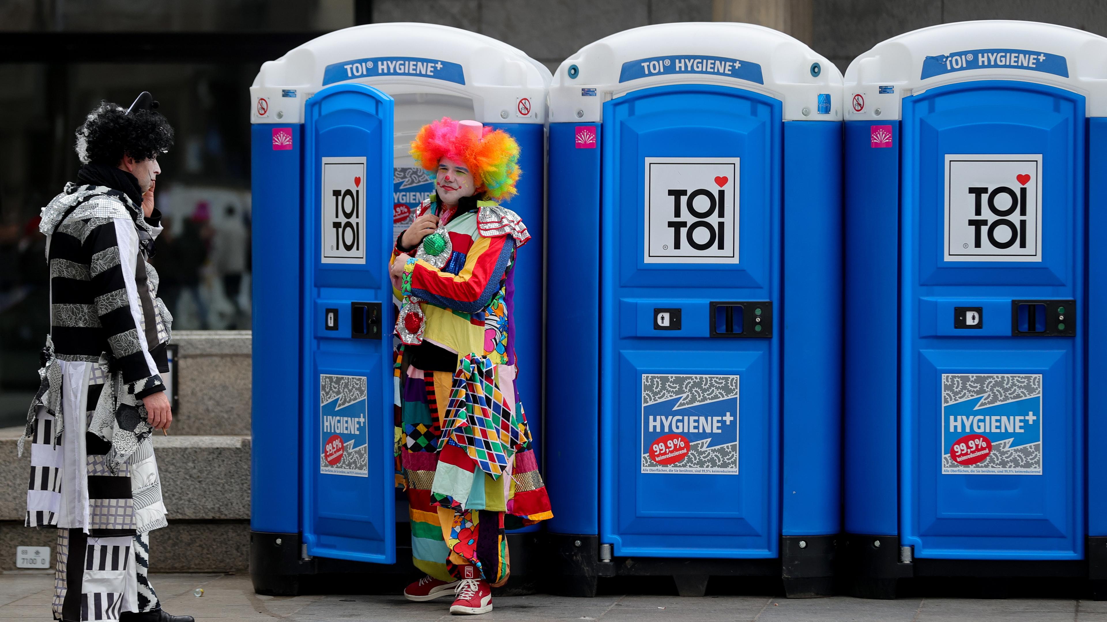 Kostümierte Nachtschwärmer vor mobilen Toiletten der traditionelle Karneval "Weiberfastnacht" (Frauenkarneval oder Fetter Donnerstag) in Köln