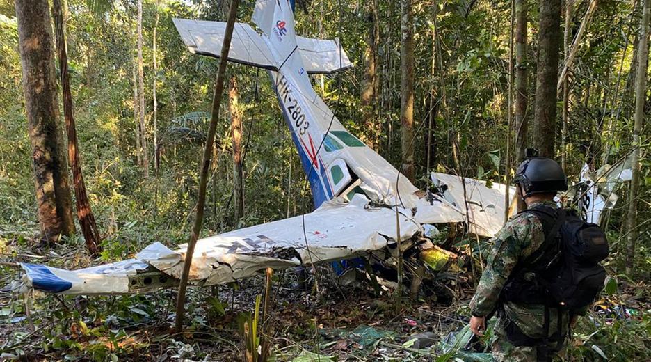 Ein Soldat steht vor einem abgestürtzen Kleinflugzeug im Regenwald.