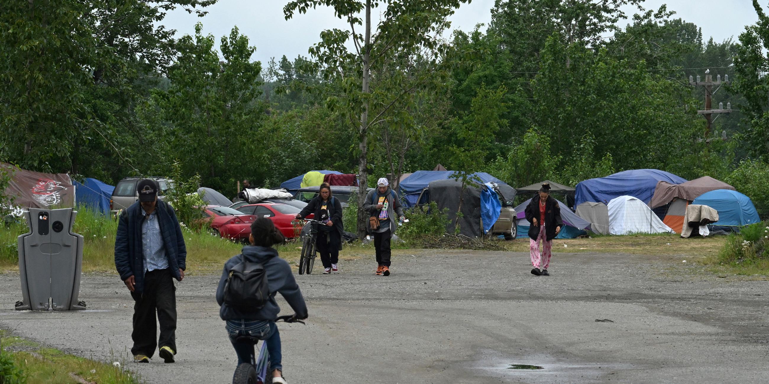 Menschen gehen in Anchorage, Alaska, von einem Obdachlosenlager zur East Third Avenue, aufgenommen am 21.06.2023