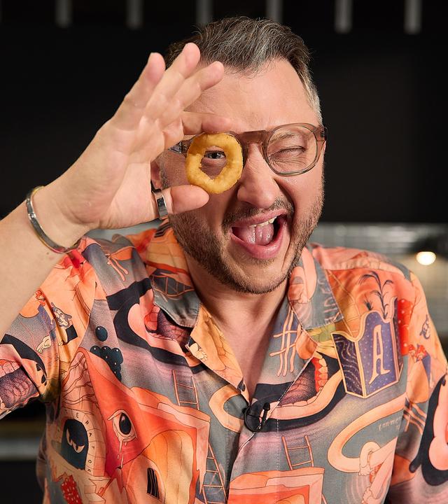 Sebastian Lege hält sich einen Zwiebelring vors Gesicht und schaut wie durch ein Fernrohr hindurch.