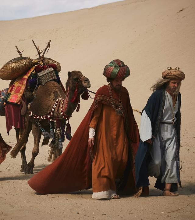 "Sketch History": In einer Wüstenlandschaft laufen drei Männer (vlnr.: Alexander Schubert, Max Giermann, Holger Stockhaus) mit Turban und bunten Gewändern hintereinander her. Der eine hält ein Kamel an der Leine, das bepackt ist mit kleinen Bronzekisten, bunten Tüchern und Trinksäcken.