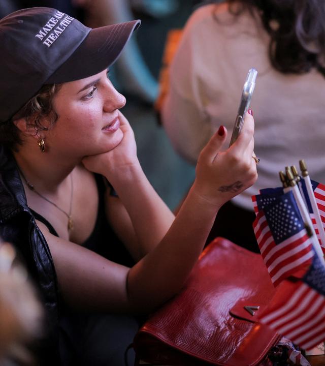 Frau, die die US-Wahlergebnisse auf dem Handy verfolgt