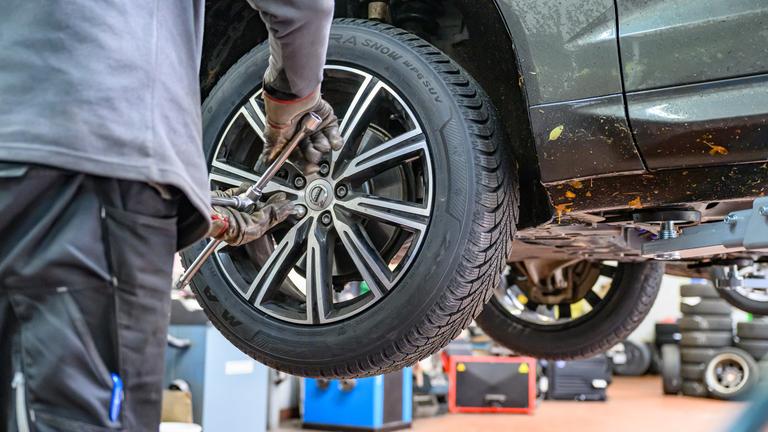 Winterreifen wird in Werkstatt an Auto montiert