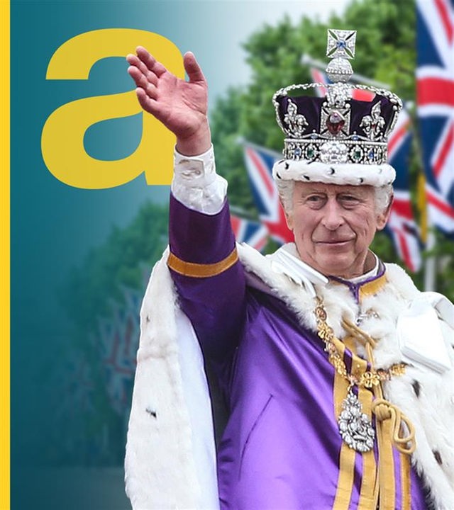 König Charles mit Krone winkt, im Hintergrund UK-Flaggen