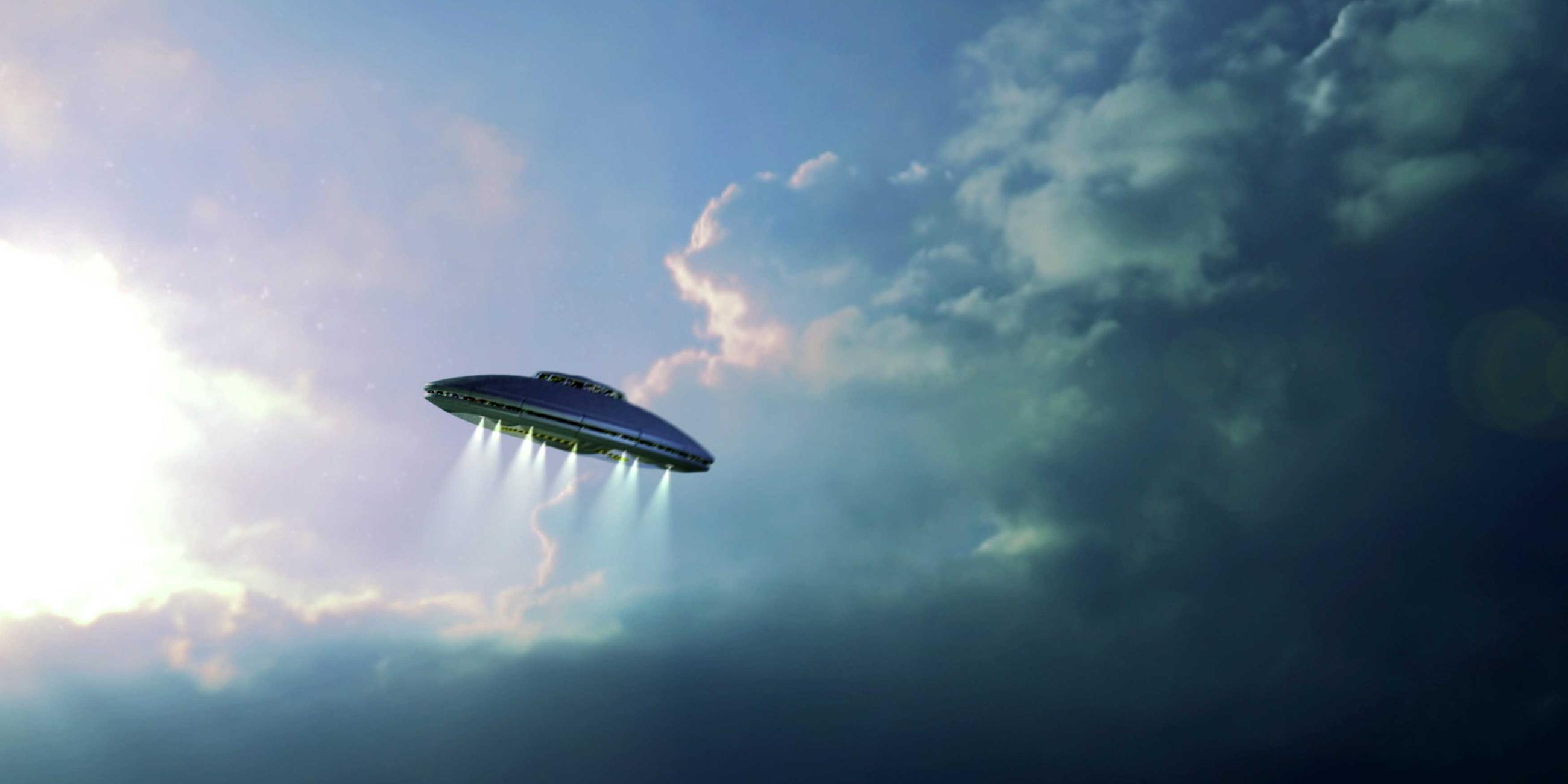  Ein Frisbee-förmiges UFO fliegt durch den Himmel. Lichtstrahlen kommen aus dem unteren Teil heraus.