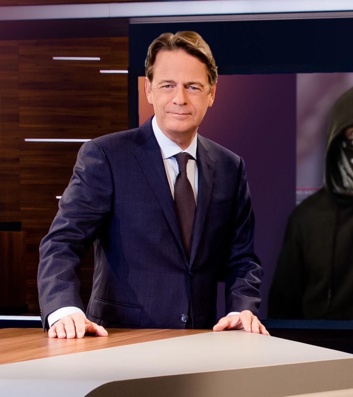 "Aktenzeichen XY... Ungelöst vom 8. Mai 2024": Moderator Rudi Cerne steht im Studio, im Hintergrund ein Bildschirm, auf dem ein Fall der Sendung abgebildet ist.  