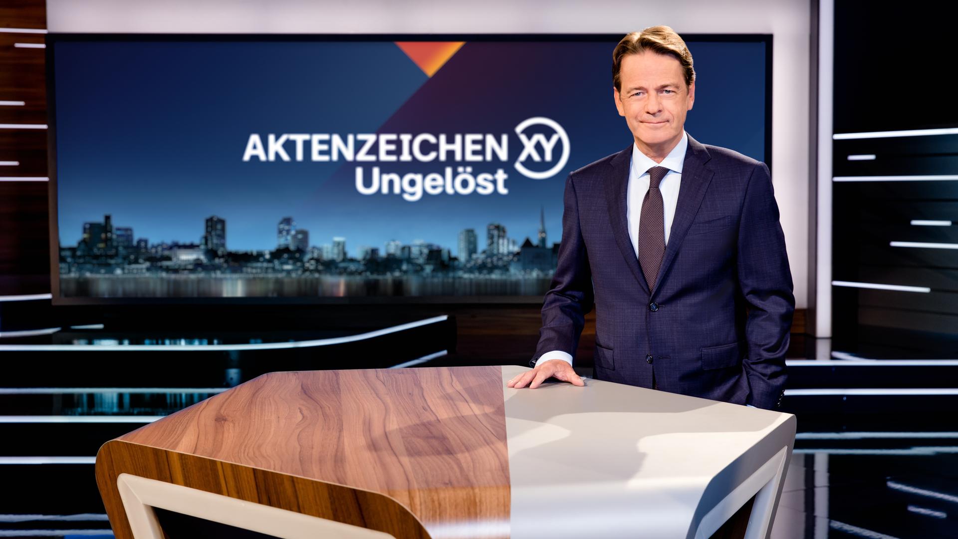 Aktenzeichen XY... Ungelöst": Moderator Rudi Cerne steht im Studio und lächelt in die Kamera.