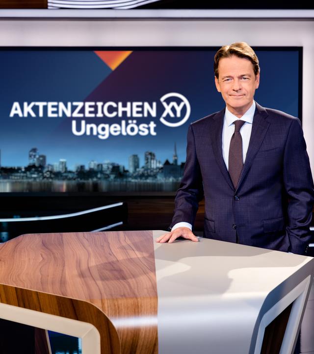 Aktenzeichen XY... Ungelöst": Moderator Rudi Cerne steht im Studio und lächelt in die Kamera.
