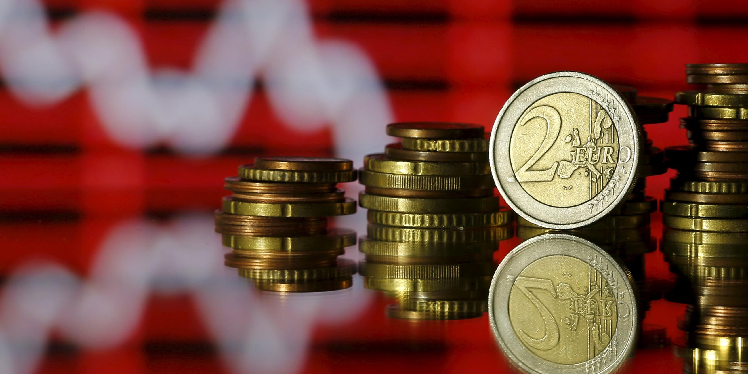 Euro- und Centmünzen vor einem Aktienkurs