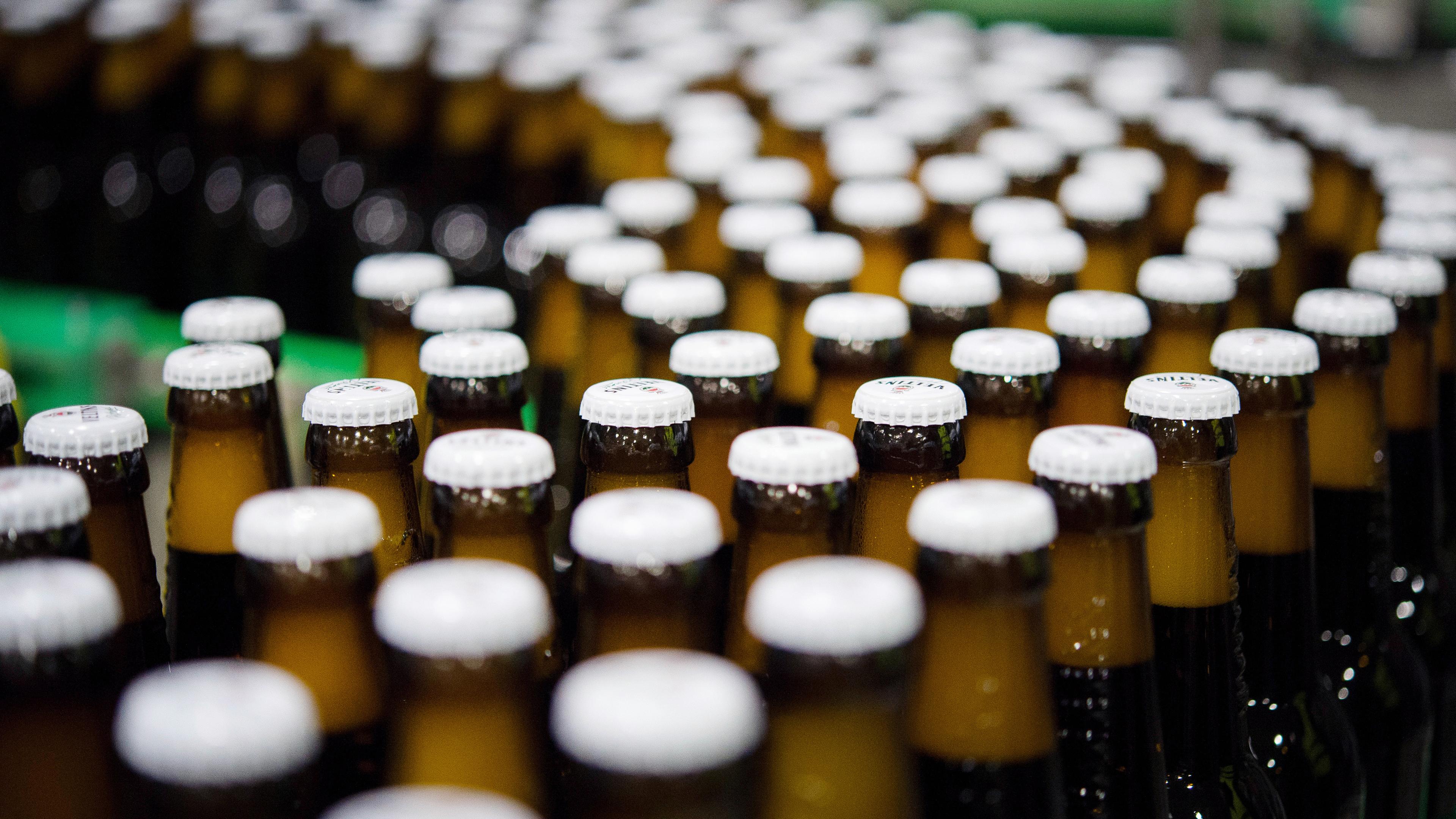 Archiv: Bierflaschen mit Kronkorken laufen durch die Produktion einer Brauerei