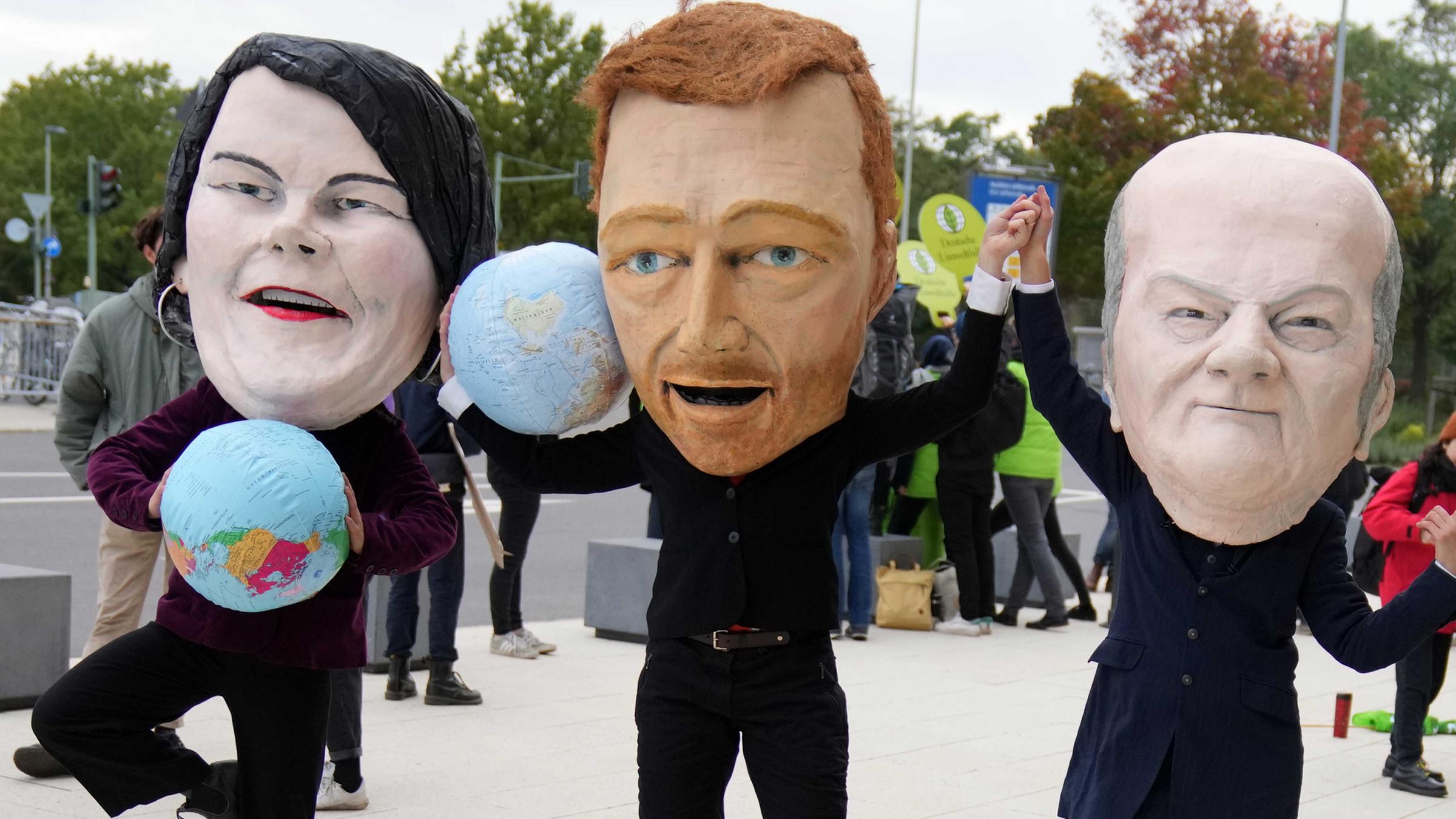 Aktivisten protestieren mit Masken, die Annalena Baerbock (l), Bundesvorsitzende von Bündnis 90/Die Grünen, Olaf Scholz (3.v.l.), SPD-Kanzlerkandidat und Bundesminister der Finanzen, und Christian Lindner (2.v.l.), Fraktionsvorsitzender und Parteivorsitzender der FDP, darstellen sollen.