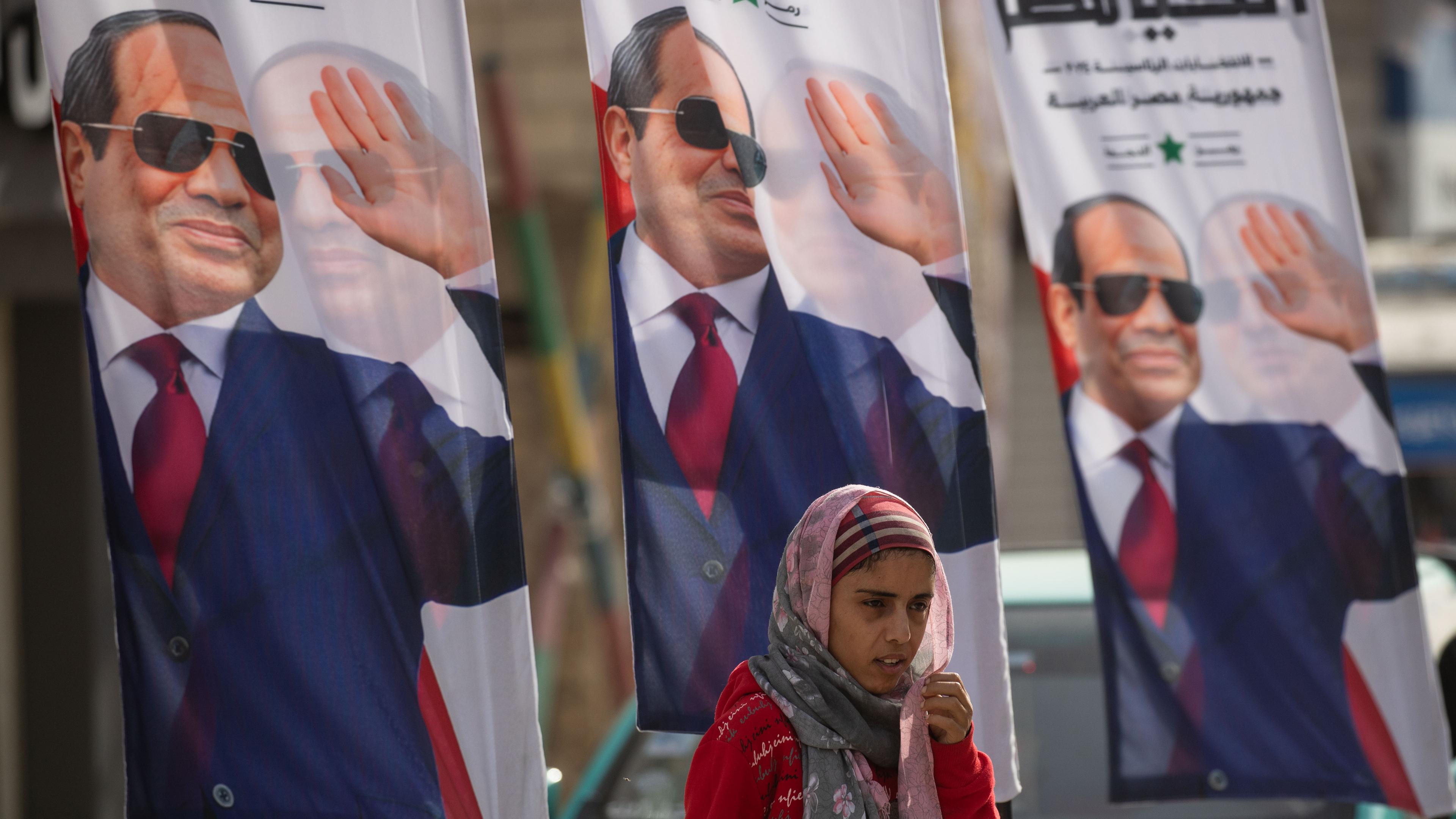 Eine Frau geht an Wahlplakaten von Ägyptens Präsident Al-Sisi vorbei.