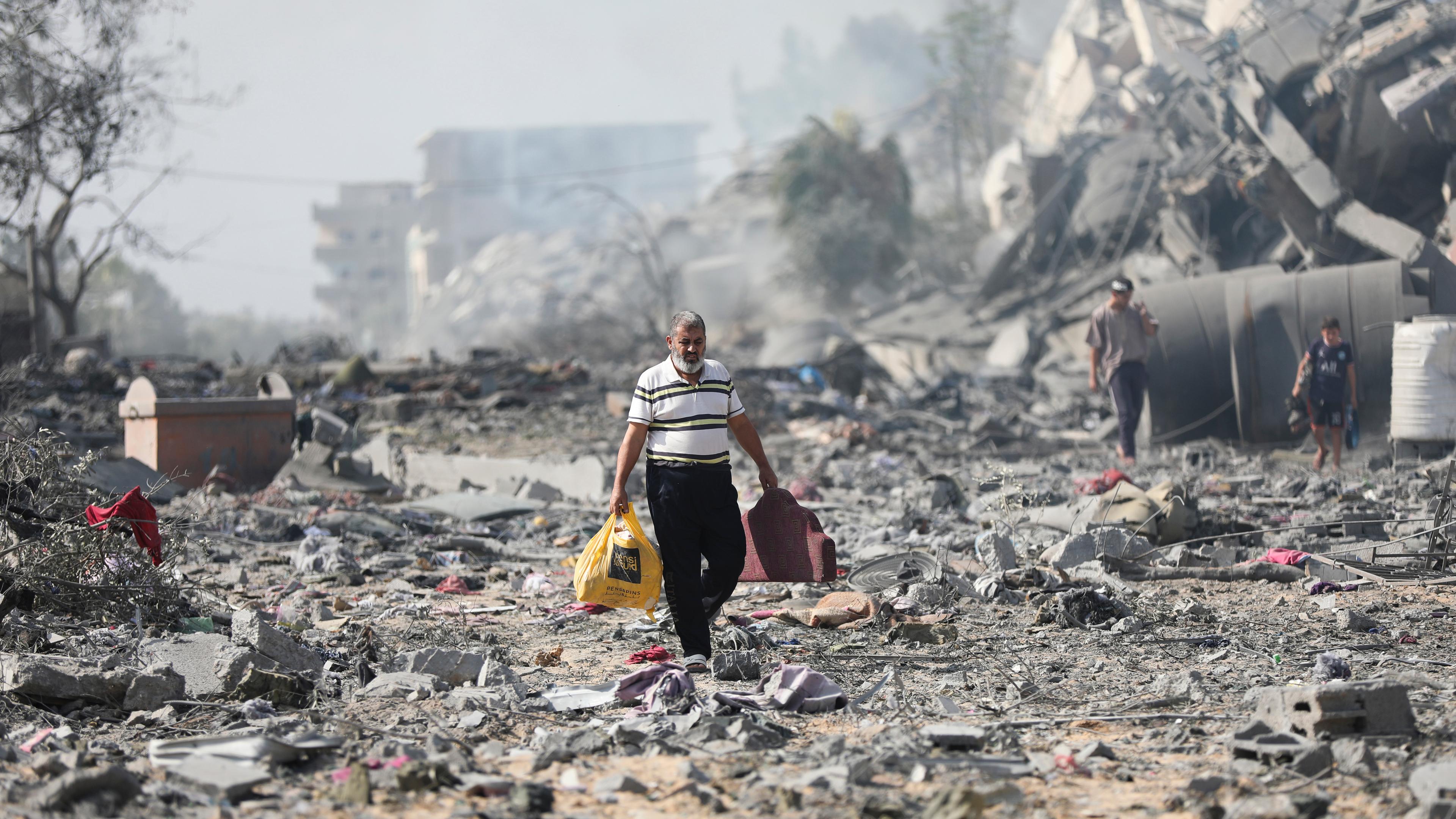 Palästinenser gehen an Gebäuden vorbei, die bei der israelischen Bombardierung auf al-Zahra am Stadtrand von Gaza-Stadt zerstört wurden