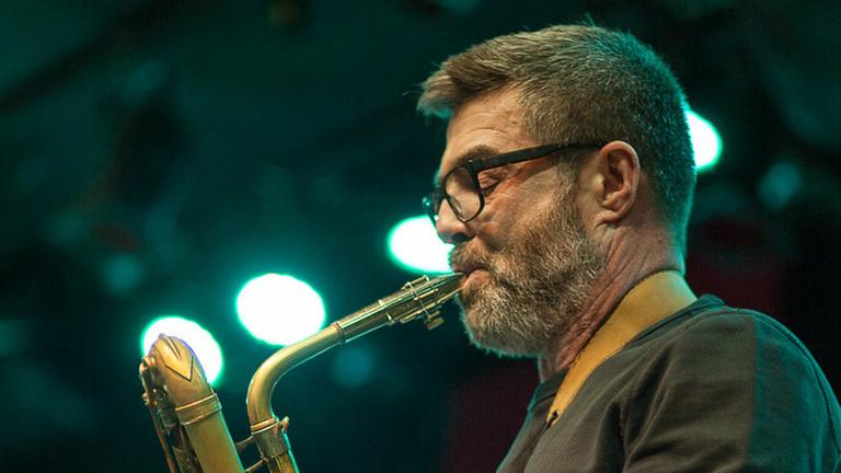 Der Saxophonist Alberto Pinton spielend, aufgenommen von der Seite.