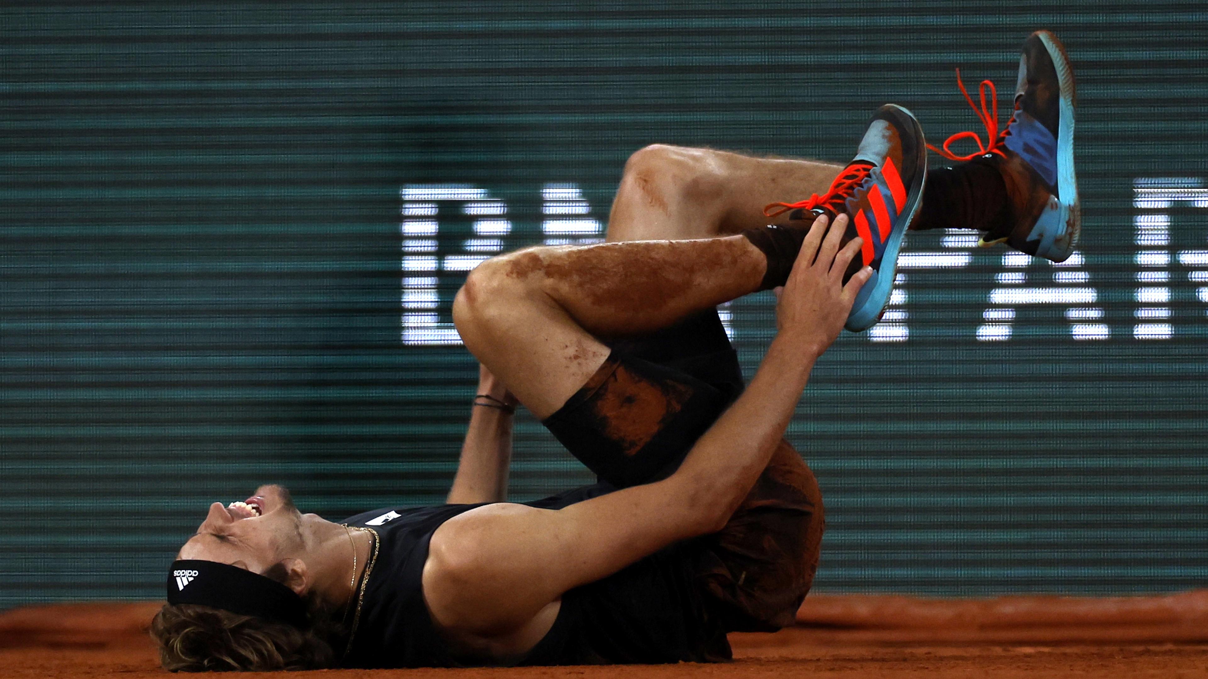 Nachdem Tennisspieler Alexander Zverev beim Halbfinale der French Open gegen Rafael Nadal umgeknickt ist, hält er sich den verletzten rechten Fuß.
