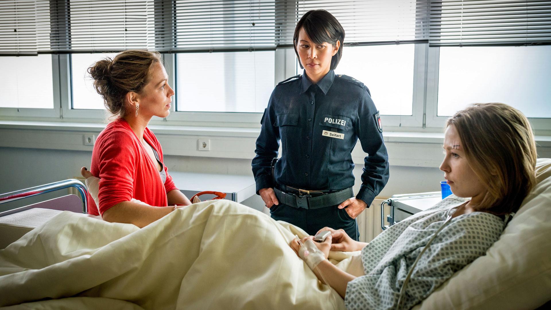 "Notruf Hafenkante - Alexas Puzzle": Im Krankenzimmer liegt Sophie Seifart (Marija Mauer) in ihrem Bett. Neben ihr sitzt ihre Mutter Tanja (Franziska Wulf), ihre Tante Alexa (Minh-Khai Phan-Thi) steht an ihrem Krankenbett.
