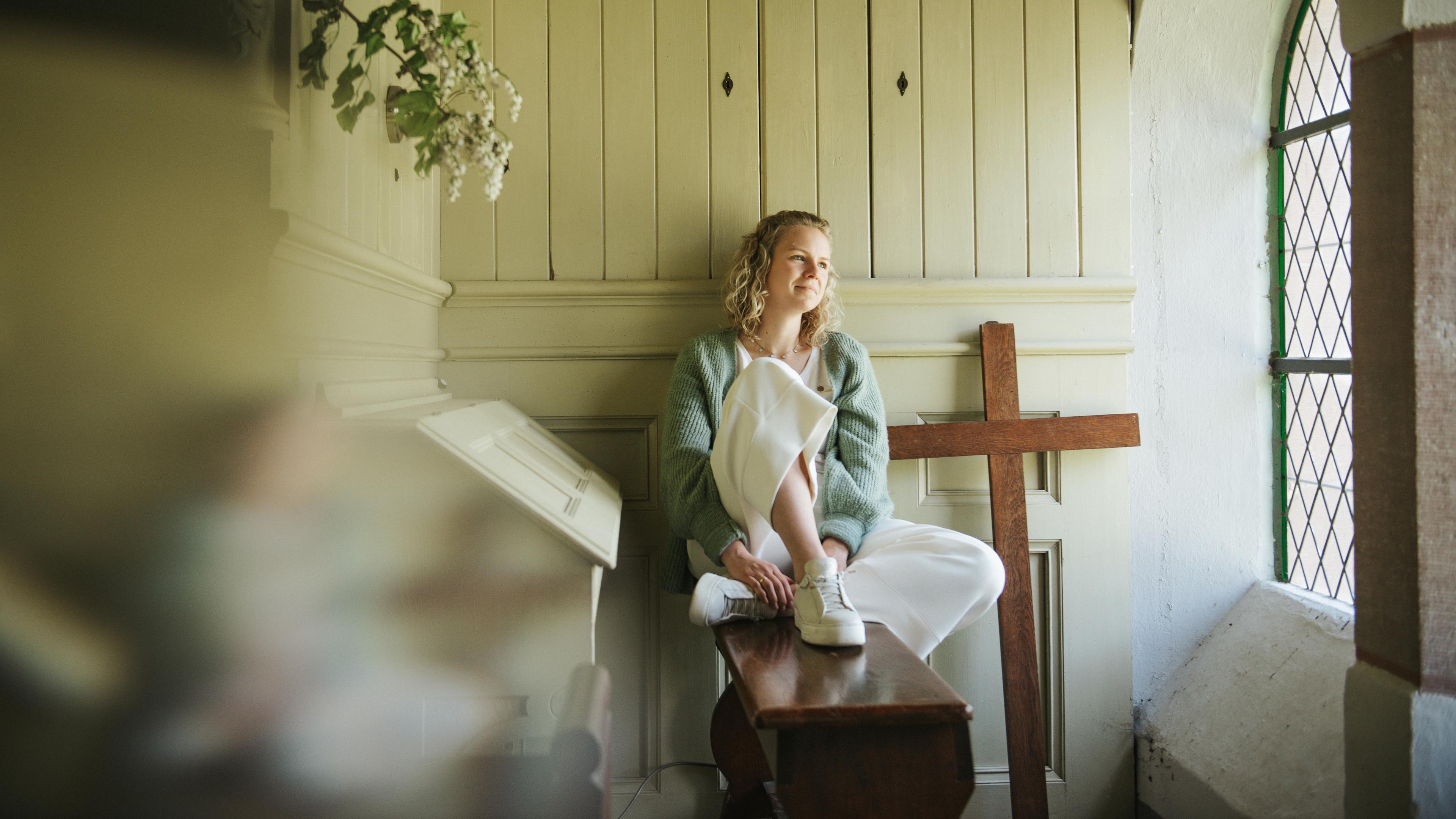 Anne sitzt neben der Orgel am Fenster.