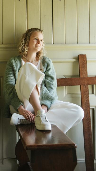 Anne sitzt neben der Orgel am Fenster.