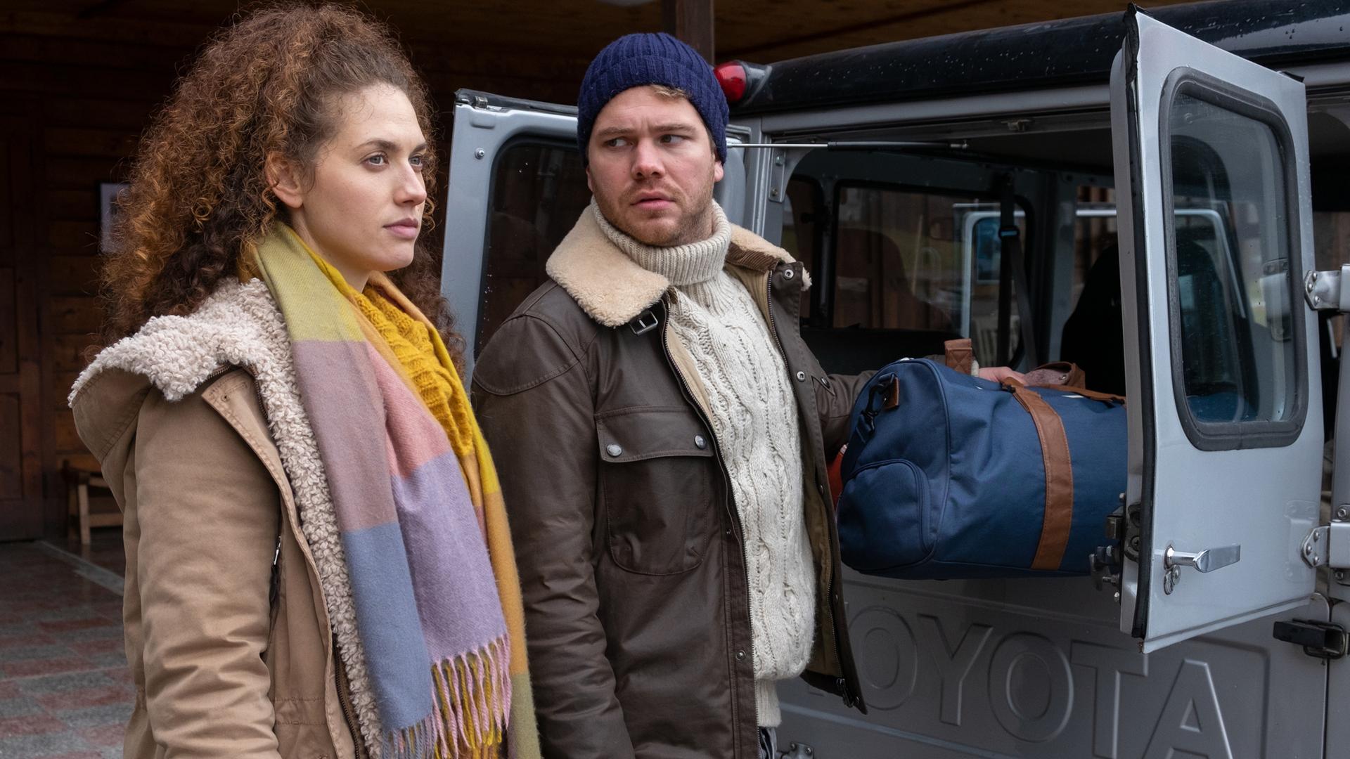 Kathi Bachmann (Fanny Krausz) lädt mit Simon Gantner (Ben Münchow) Gepäck in ein Auto ein.