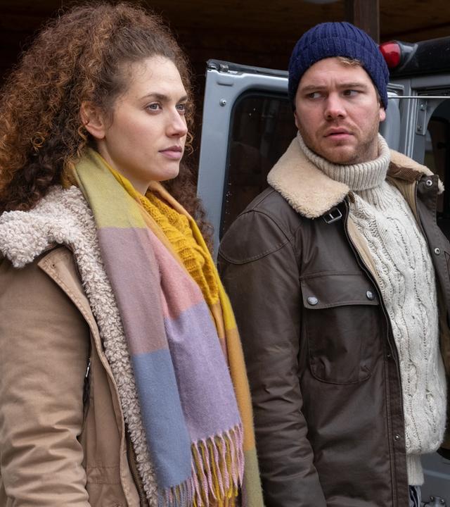 Kathi Bachmann (Fanny Krausz) lädt mit Simon Gantner (Ben Münchow) Gepäck in ein Auto ein.