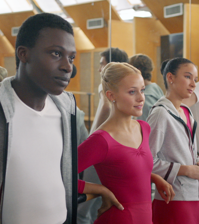 Isaac, Lena, Ines, Max und Jeff (v.l.n.r.) lehnen gemeinsam an der Ballettstange im Unterrichtsraum der Balettschule. Die Wand hinter ihnen ist verspiegelt.
