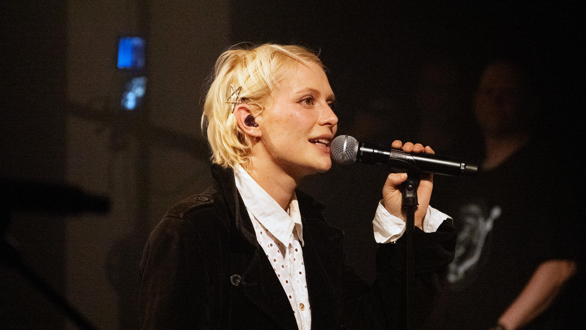 Alli Neumann singt in ein Mikrofon.