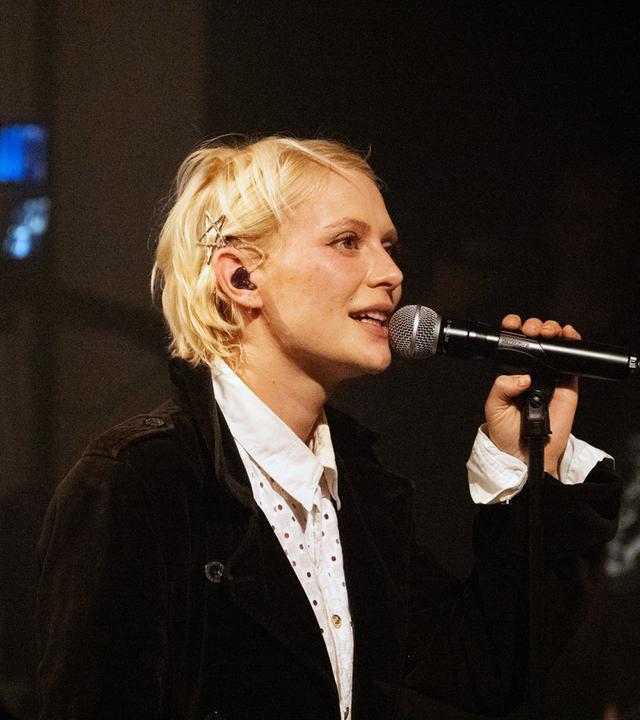 Alli Neumann singt in ein Mikrofon.