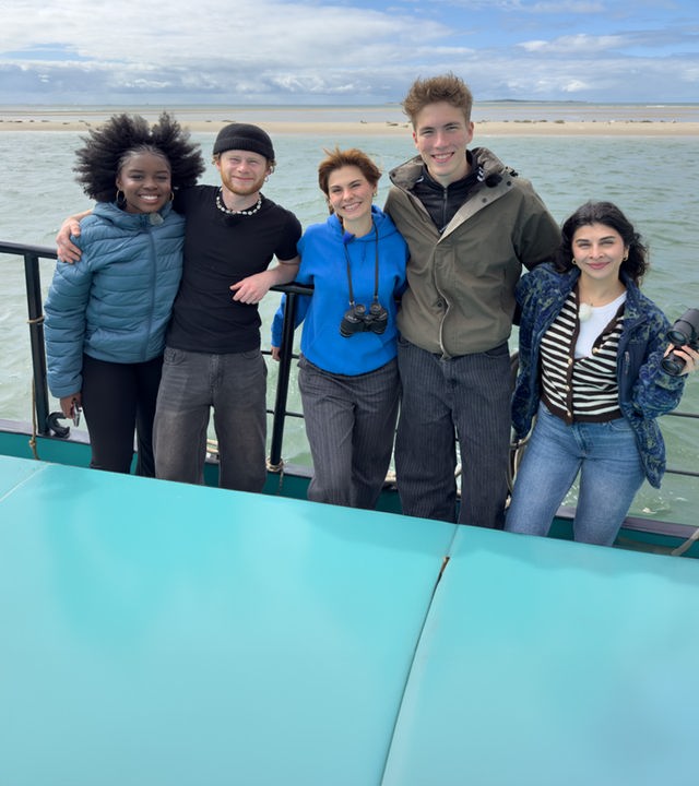 Jafait, Justus, Angelina, Rouven und Ella stehen auf einem Segelboot - im Hintergrund eine Sandbank mit Seehunden