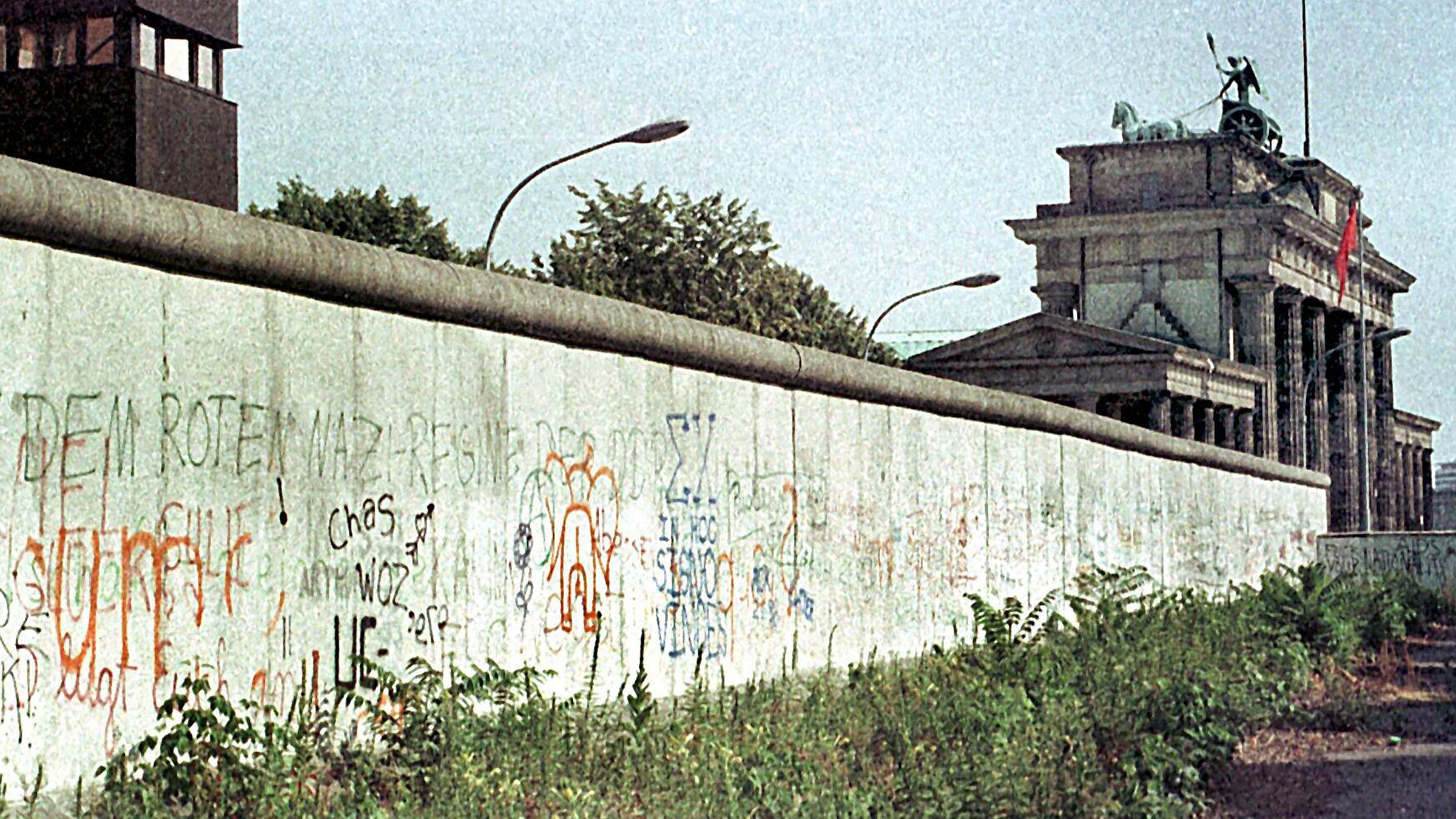 Das Archivbild vom August 1984 zeigt die Berliner Mauer mit einem Wachturm (l) am Brandenburger Tor (r).