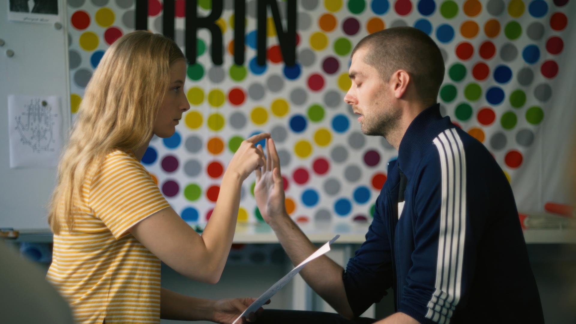 Ein Mann und eine Frau sitzen sich gegenüber und berühren sich an der Hand.