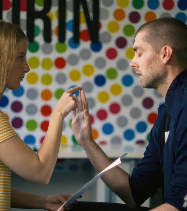 Ein Mann und eine Frau sitzen sich gegenüber und berühren sich an der Hand.