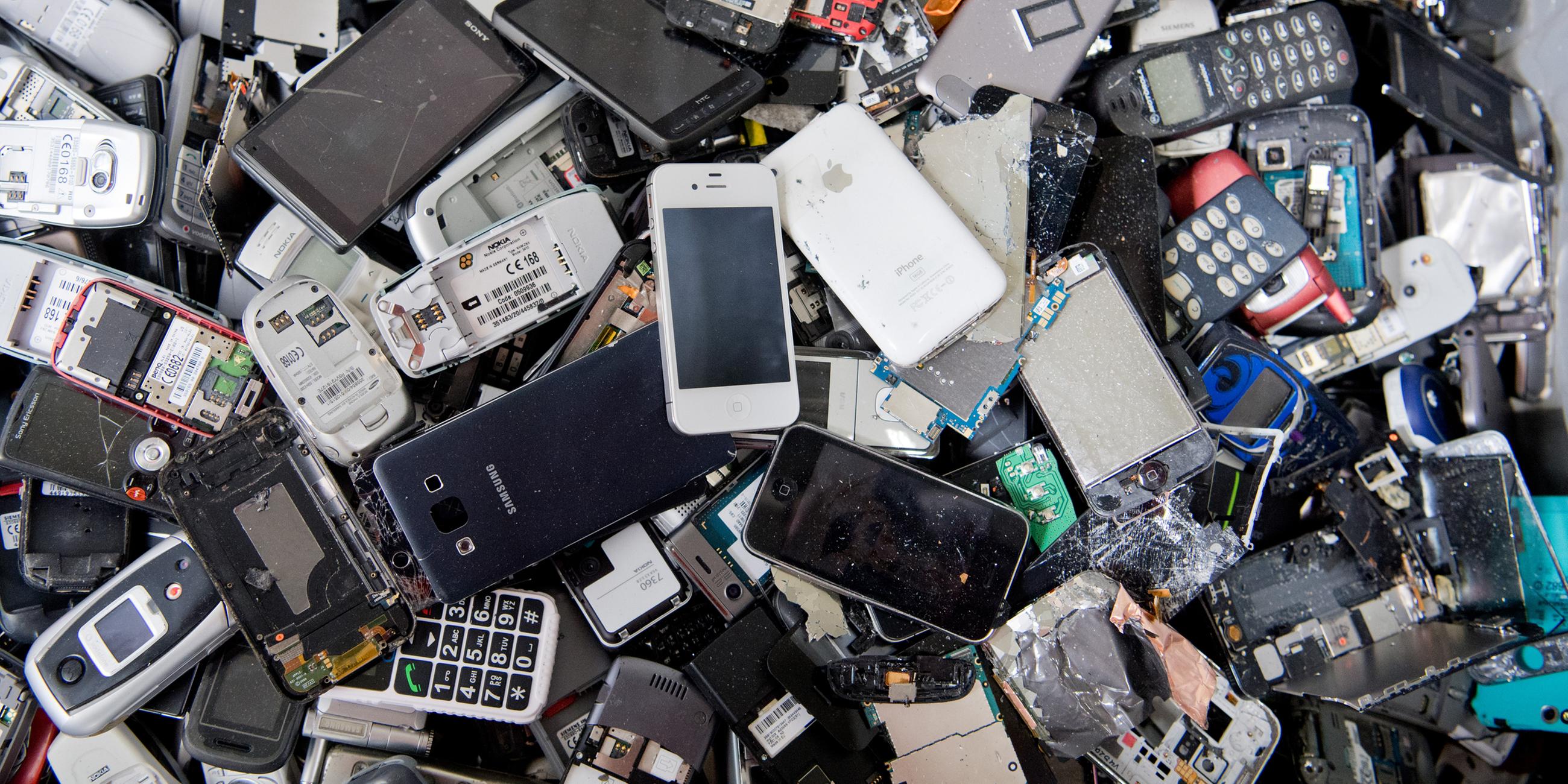 Alte Handys und Smartphones liegen in einem Container, ehe sie geschreddert werden
