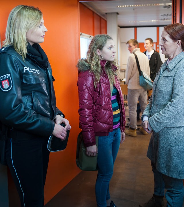 "Notruf Hafenkante - Alte Schule": Melanie (Sanna Englund) steht im Schulflur und beobachtet wie Frau Blume (Annette Kreft) mit ihrer Schülerin Alina (Charleen Deetz) spricht.