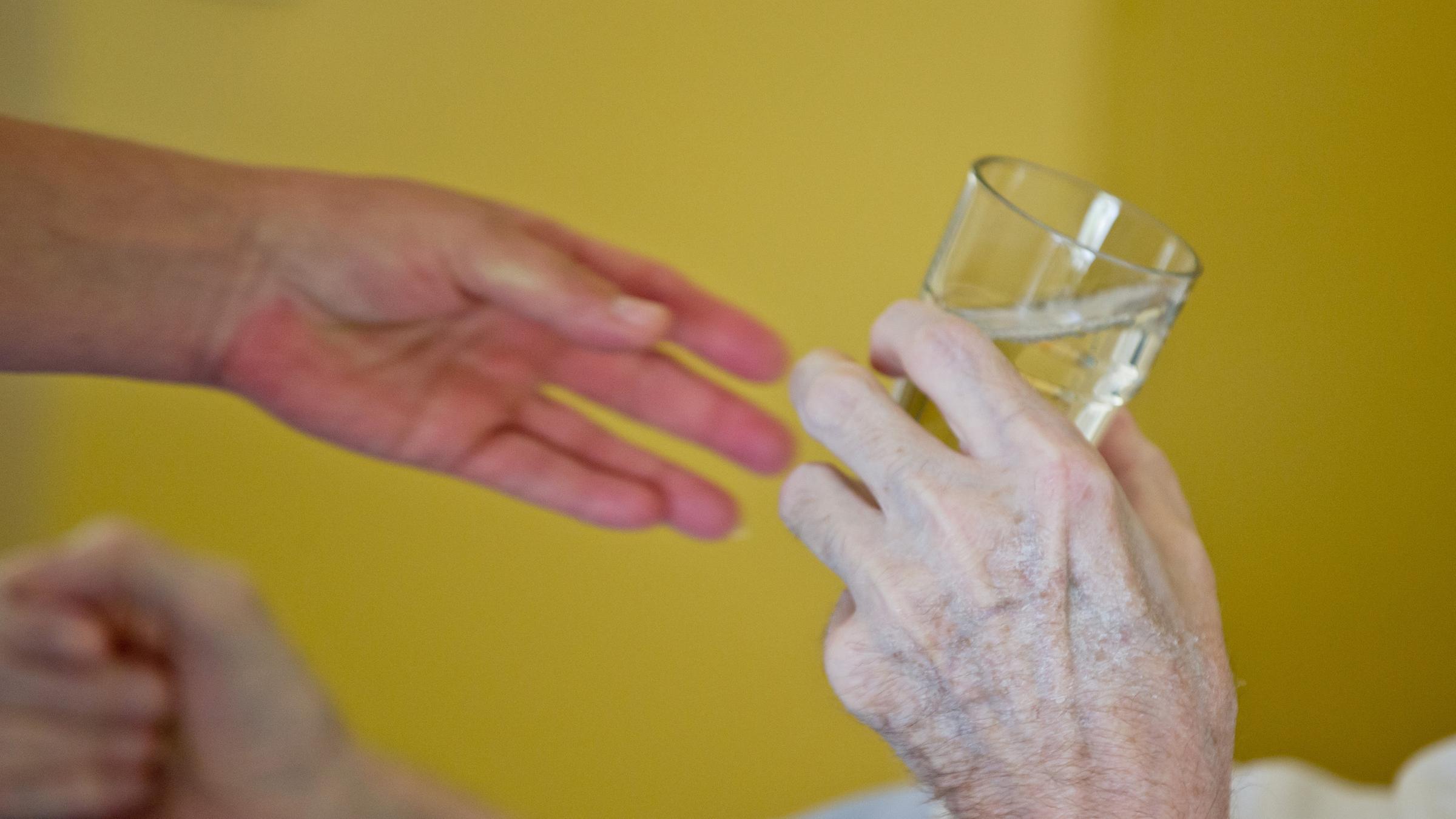 Eine Pflegerin reicht einem Patienten ein Glas Wasser