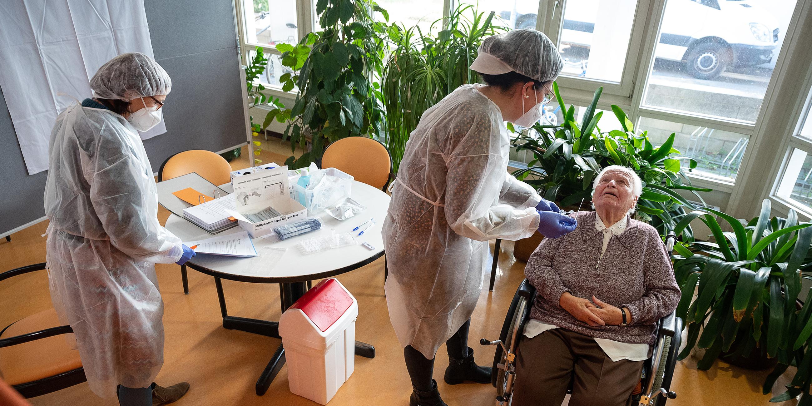 Altenpflegerinnen machen Coronatest bei Seniorin