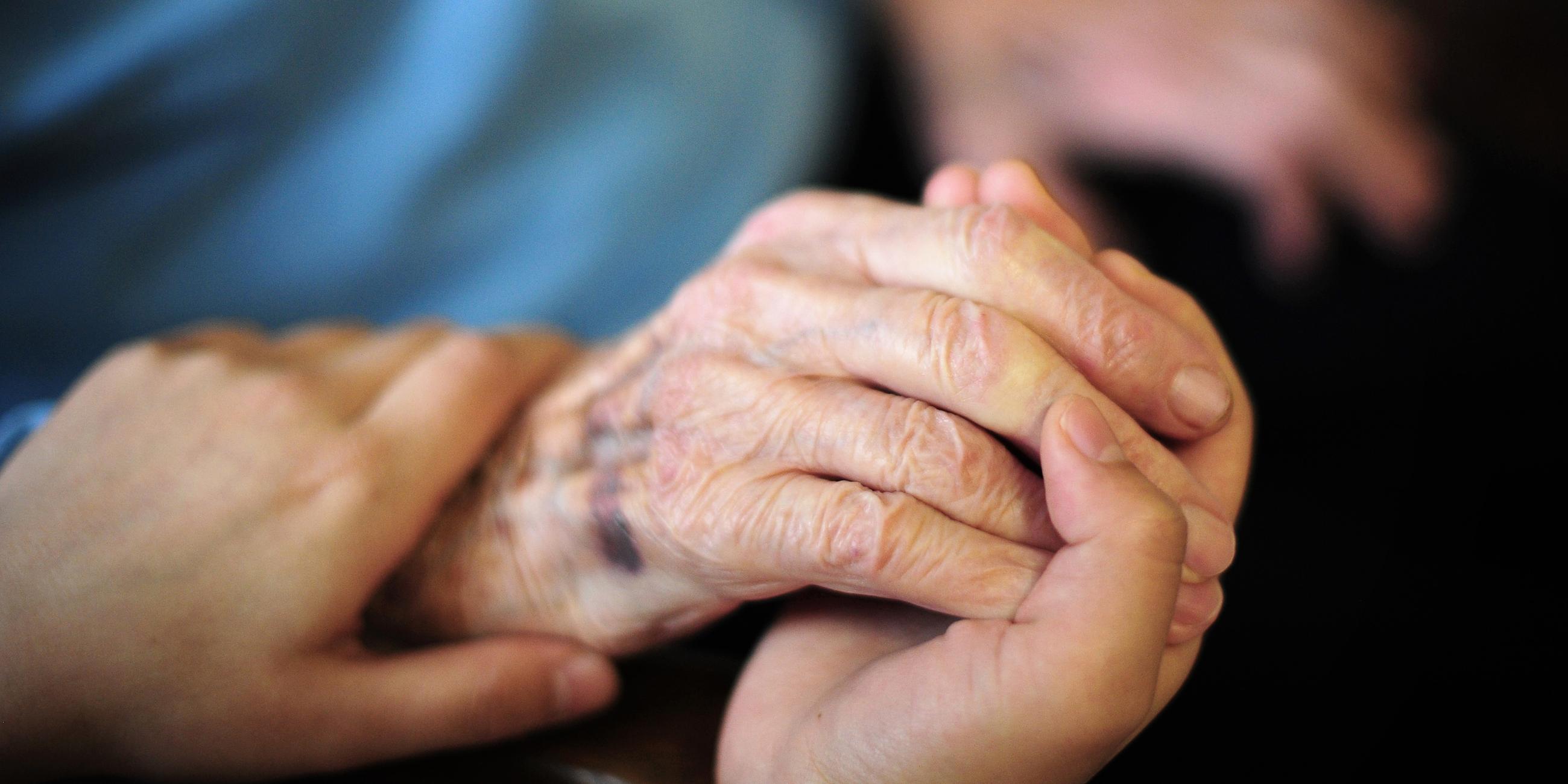 Eine Pflegekraft hält in einem Seniorenheim die Hand einer Bewohnerin, aufgenommen am 23.01.2014