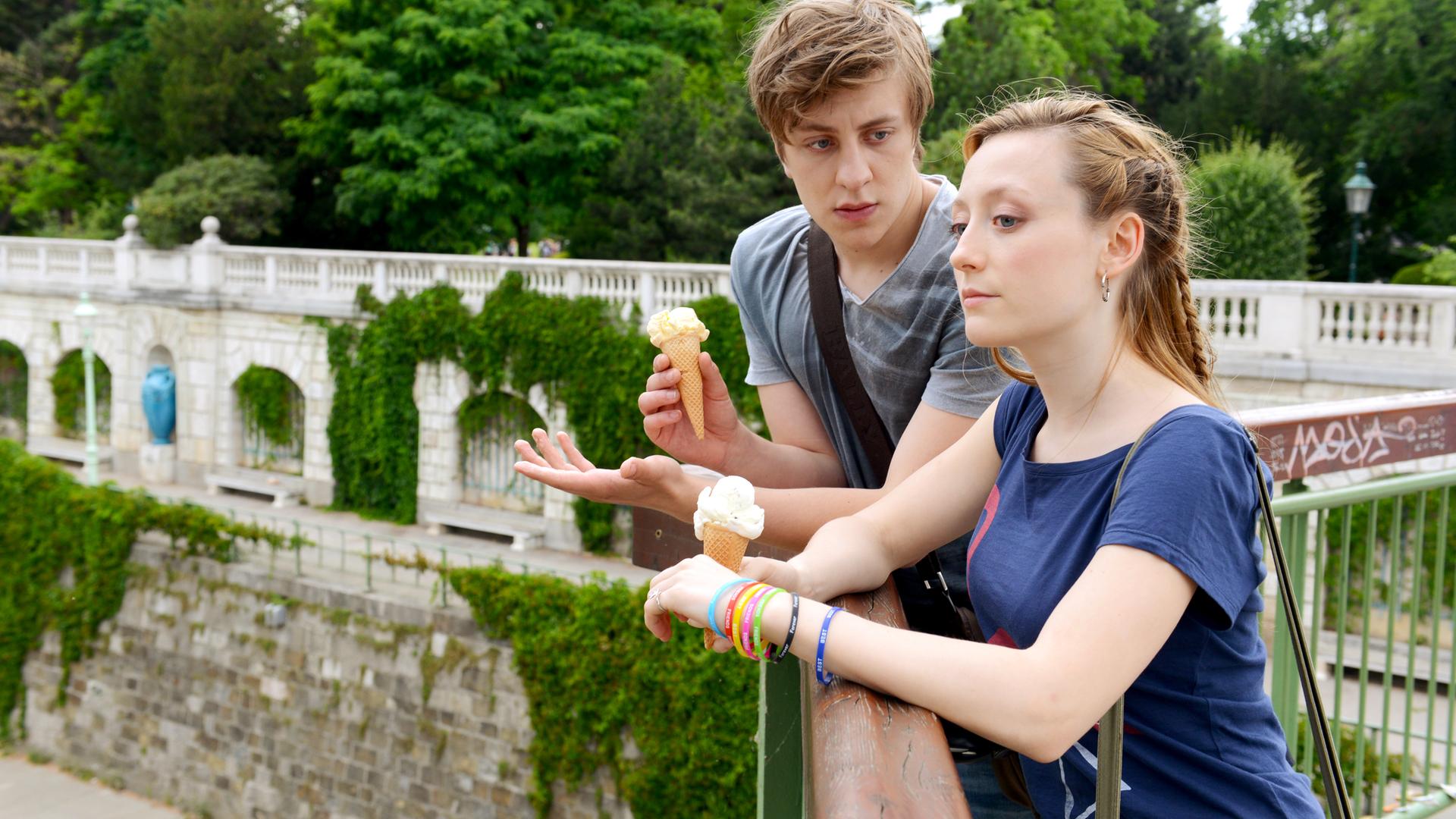 Thomas Schubert (Ben), Alina Fritsch (Hanna) stehen an einem Geländer in einem Park.