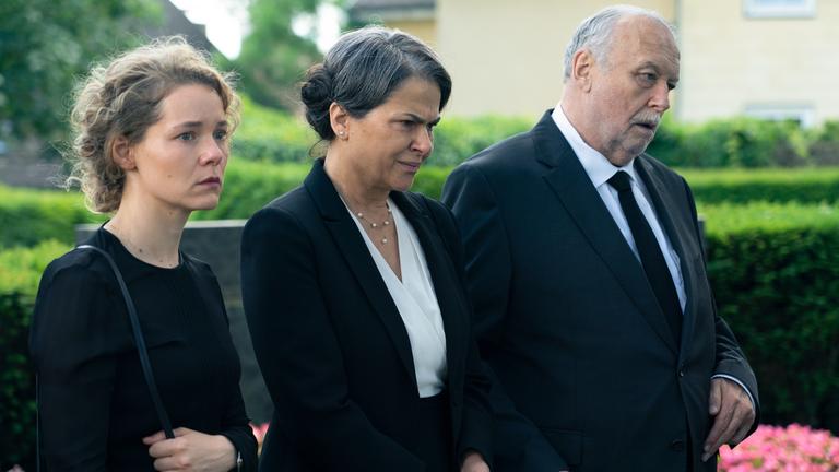 "Am Ende - Die Macht der Kränkung - Mirjam": Julia (Angelina Häntsch), Rosa (Barbara Auer) und Josef (Thomas Thieme) stehen nebeneinander und blicken in die Ferne. Im Hintergrund sind Hecken und Blumen zu sehen.