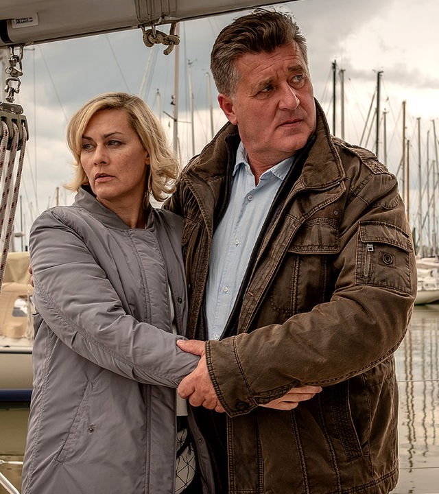 Ines Hauber (Gesine Cukrowski) und Hans Moor (Bruno F. Apitz) stehen nebeneinander Arm in Arm auf einem Steg an dem viele Segelboote liegen.