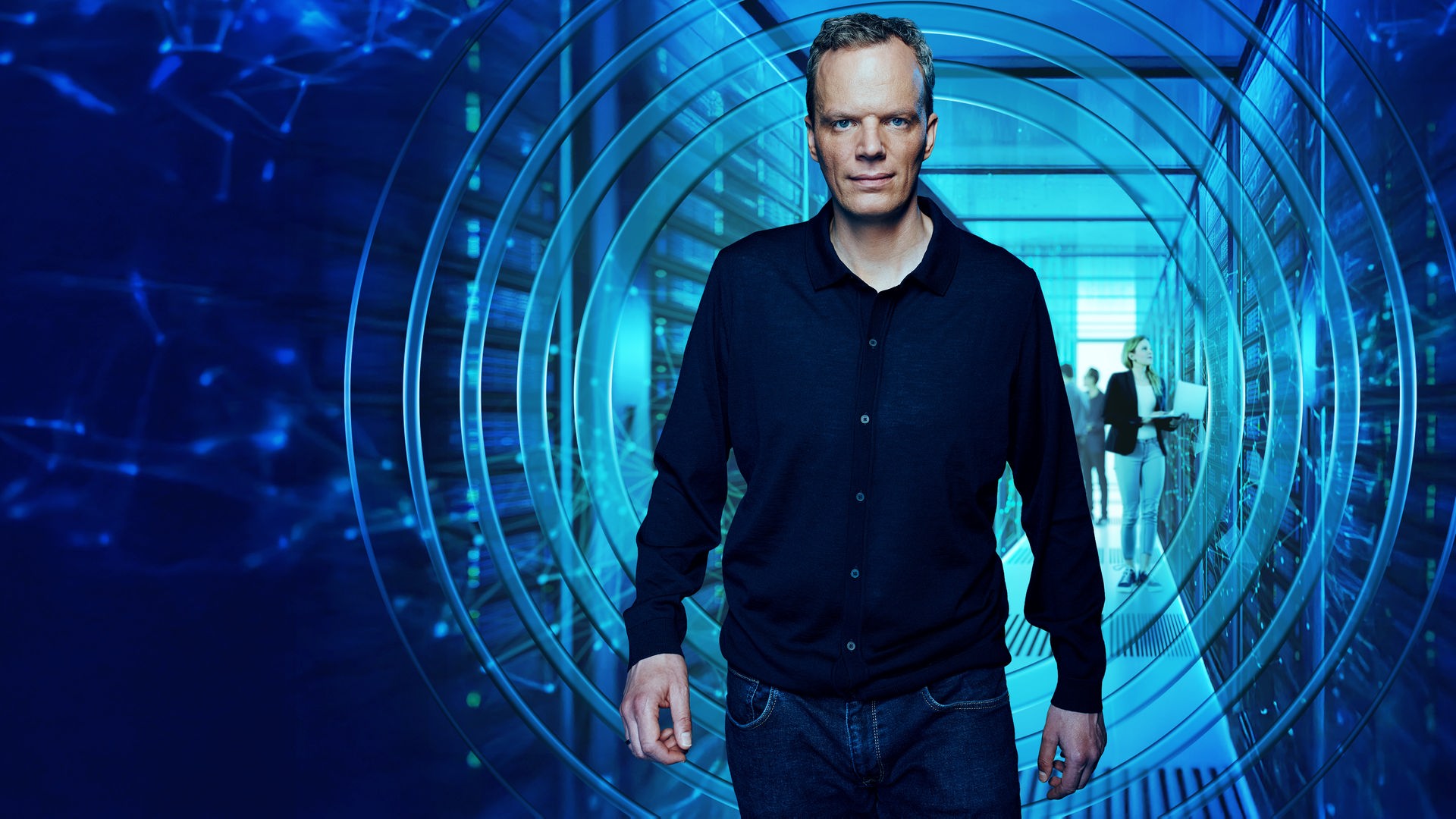 ZDF-Wirtschaftsexperte Florian Neuhann kommt auf den Betrachter zu, während im Hintergrund Menschen an Servern arbeiten