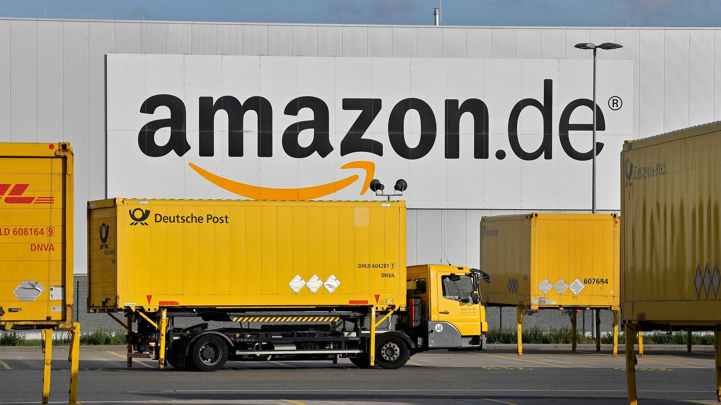 Ein Lastwagen steht vor einer Lagerhalle mit der Aufschrift "amazon.de".