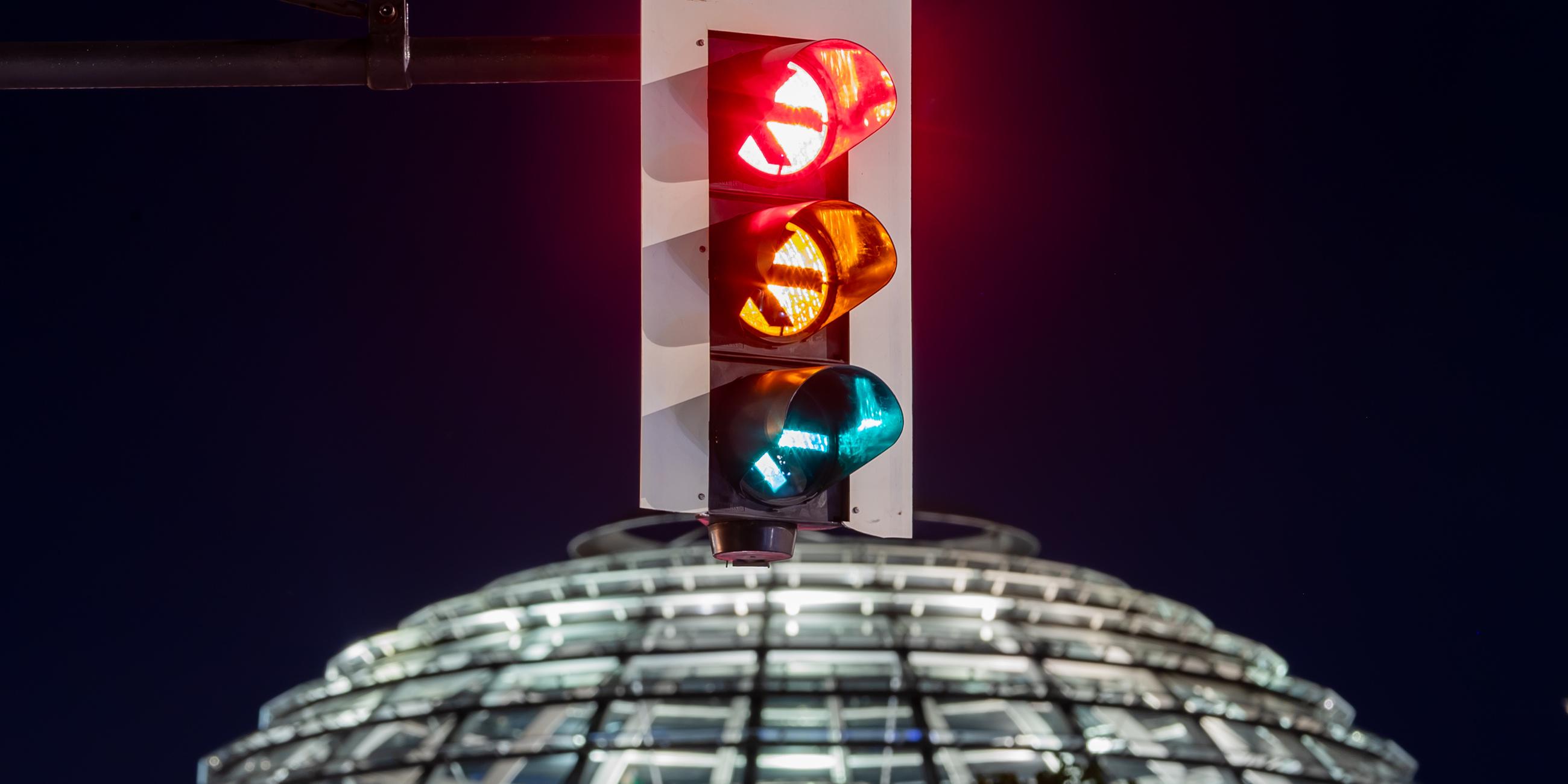 Berlin: Eine Ampel vor der Kuppel des Reichstagsgebäudes leuchtet in einer Langzeitbelichtung in allen drei Phasen. Der Parteivorstand der SPD hat der Aufnahme von Koalitionsgesprächen mit Grünen und FDP zugestimmt.