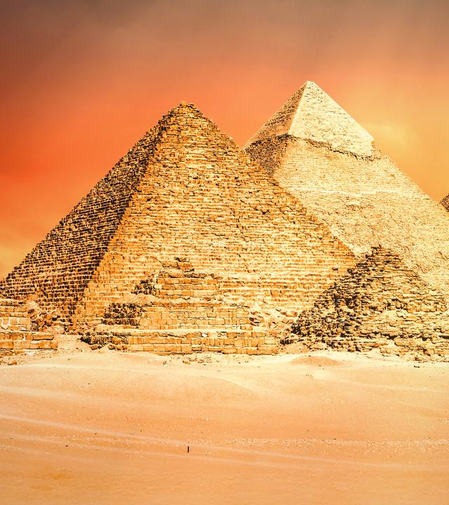 Die großen ägyptischen Pyramiden vor einem bedrohlichen rostroten Himmel.