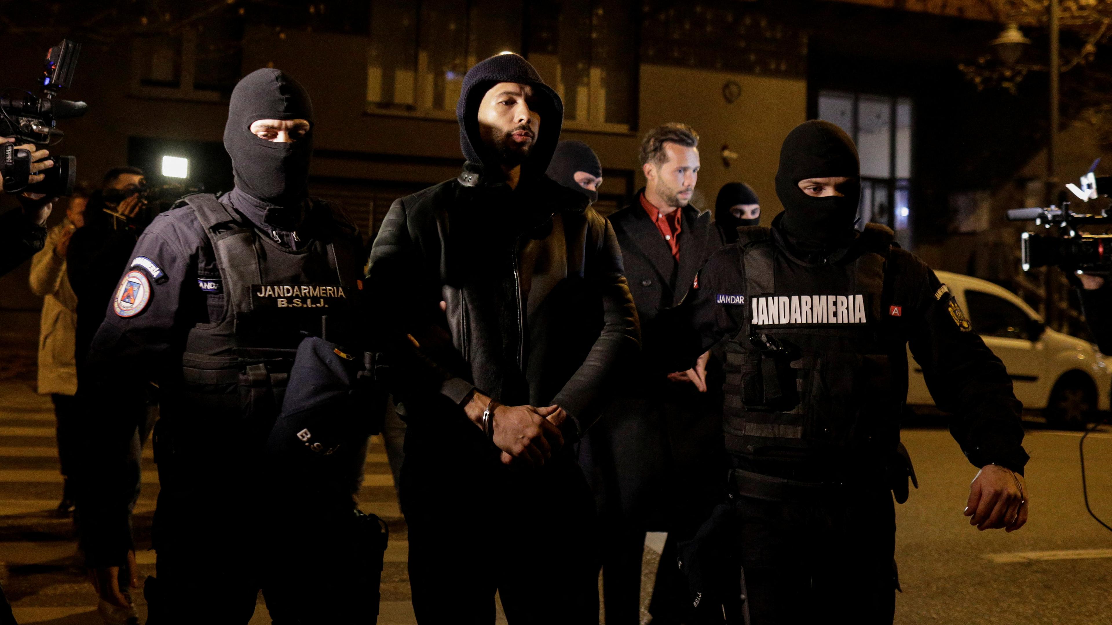 Andrew Tate und Tristan Tate werden von Polizisten vor dem Hauptquartier der Direktion zur Untersuchung von organisierter Kriminalität und Terrorismus in Bukarest (DIICOT) eskortiert