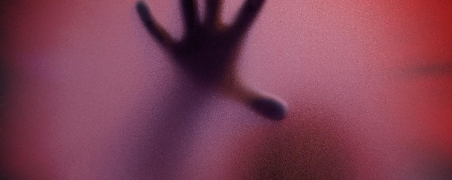 Schatten eines Menschen durch eine matte Glasscheibe in Rottöne getaucht