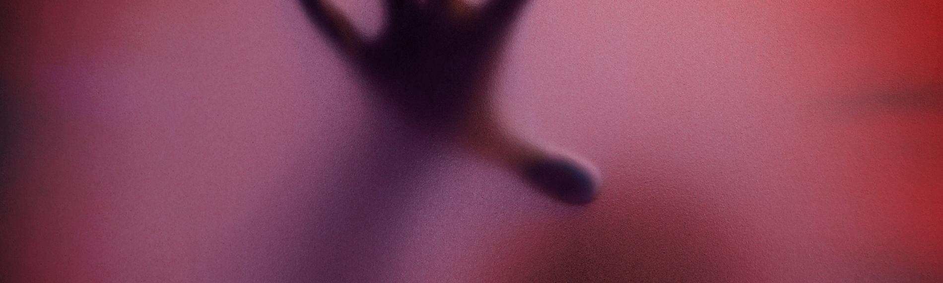 Schatten eines Menschen durch eine matte Glasscheibe in Rottöne getaucht