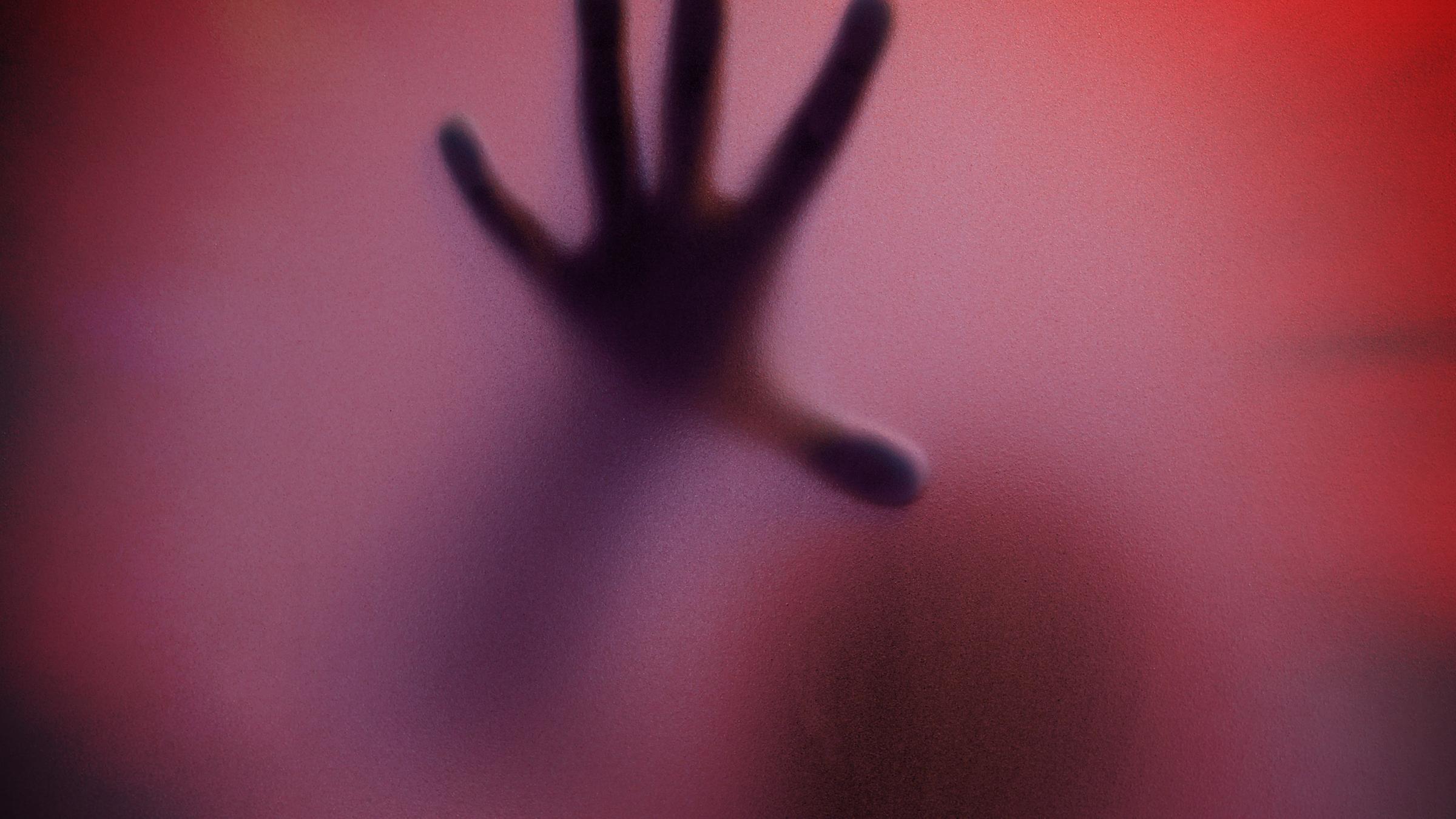 Schatten eines Menschen durch eine matte Glasscheibe in Rottöne getaucht