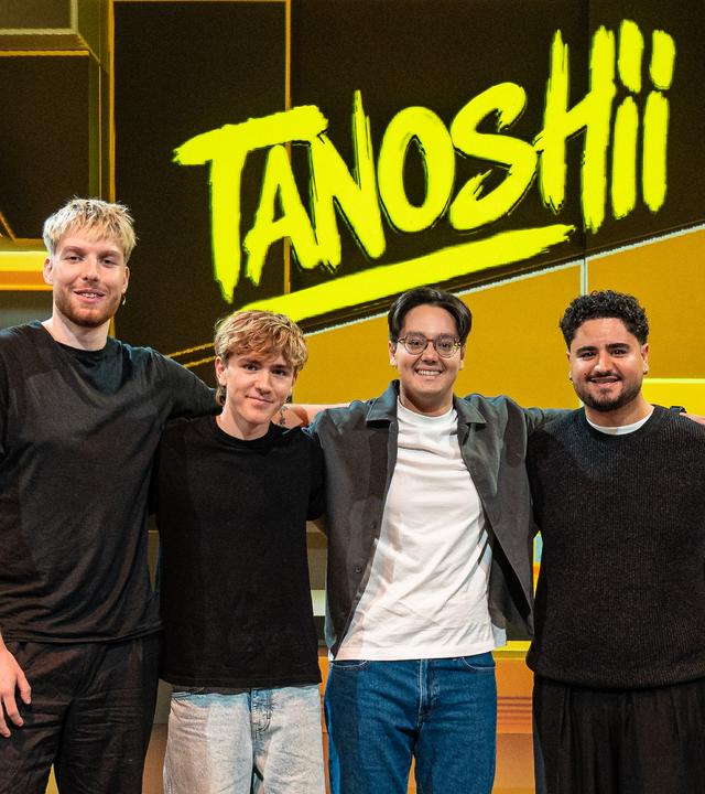 Tanoshii: Die Creators Anigents, Louis, Musa und Azizkazama stehen Arm in Arm im Tanoshii-Studio. In ihrer Mitte steht der Moderator der Sendung, Raafey.