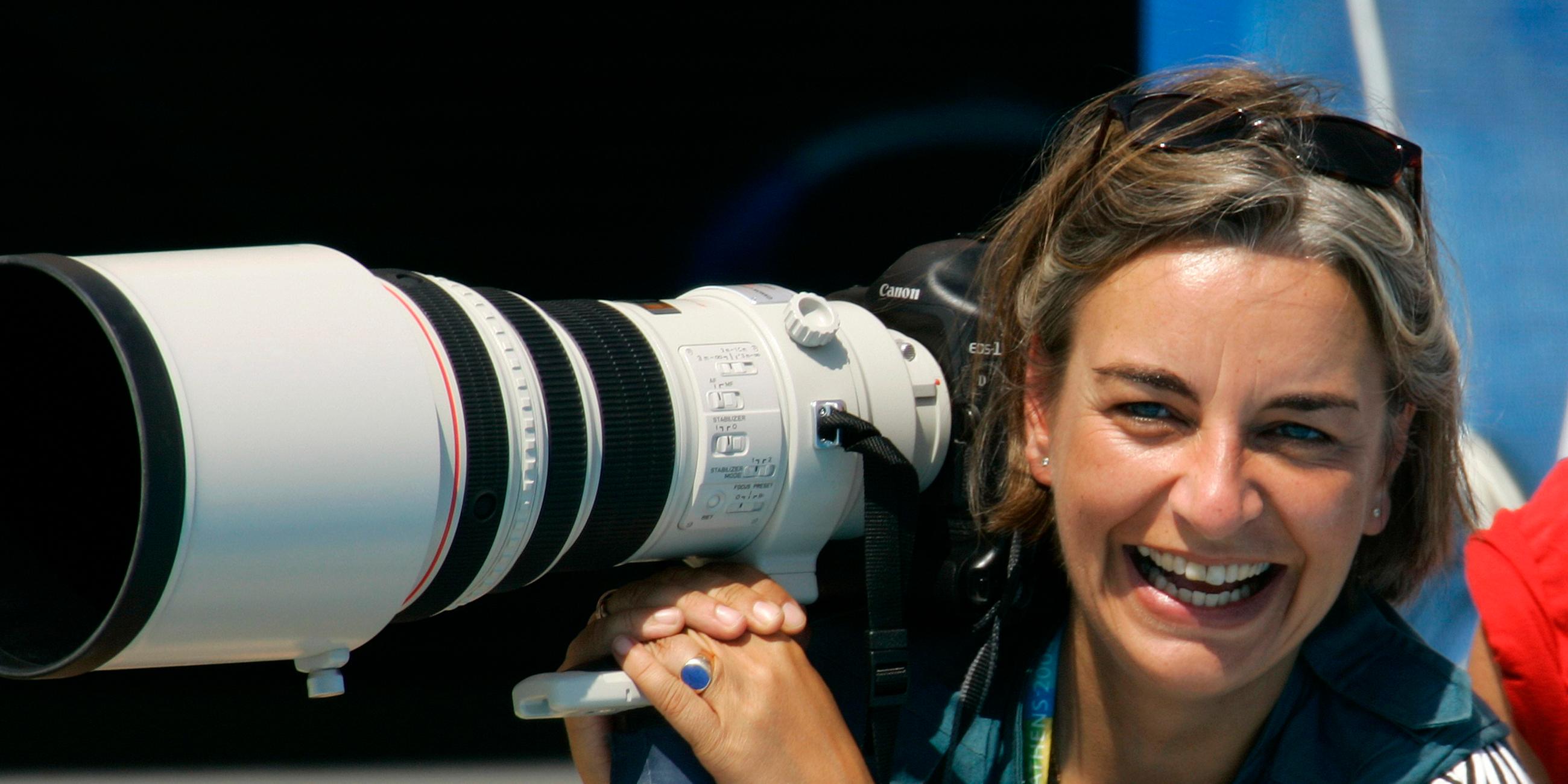 Fotografin Anja Niedringhaus lacht, in ihrer Hand hält sie eine Fotokamera.